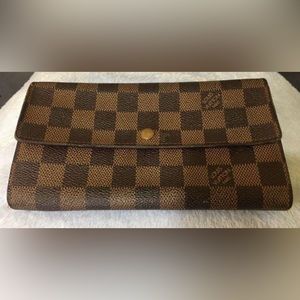 Sarah' wallet by Louis Vuitton is done in Damier ebene canvas.